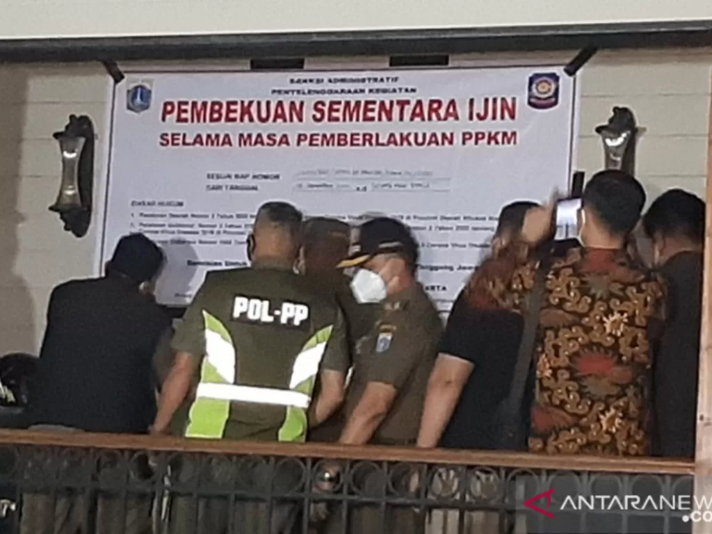 Petugas dari Satuan Polisi Pamong Praja DKI Jakarta menempelkan spanduk pembekuan sementara izin beraktivitas Holywings Kemang (ANTARA/Sihol Hasugian)