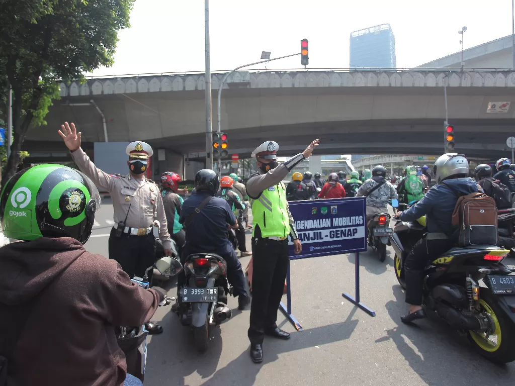Polisi berjaga untuk mengarahkan kendaraan saat penerapan sistem ganjil genap di Jalan Gatot Subroto (ANTARA FOTO/ Reno Esnir/hp.)