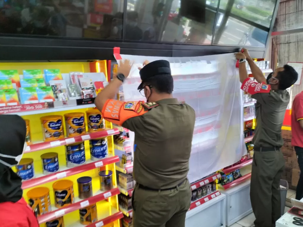 Kepala Ketenteraman, Ketertiban Umum dan Operasional Satpol PP Jakarta Barat Ivand Sigiro saat menutup pajangan produk rokok di salah satu toko swalayan kecil di Jakarta Barat, Senin (12/9/2021). (ANTARA/Walda)