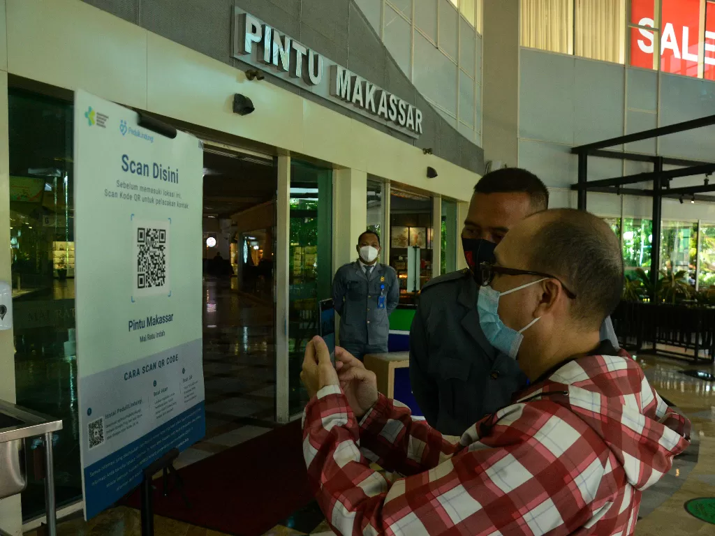 Warga memindai QR Code melalui aplikasi PeduliLindungi saat akan memasuki Mall. (Foto: ANTARA/Abriawan Abhe)