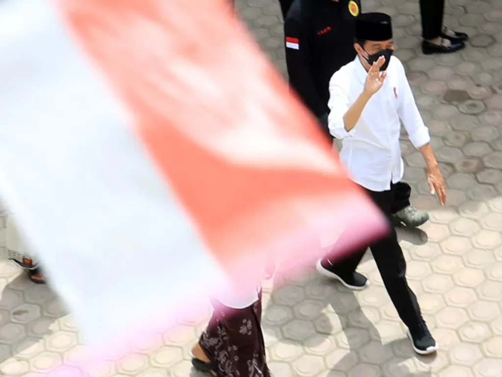 Presiden Joko Widodo melambaikan tangan kepada santri saat meninjau vaksinasi COVID-19 di Pesantren Istiqamatuddin Darul Muarif. (ANTARA FOTO/Syifa Yulinnas)