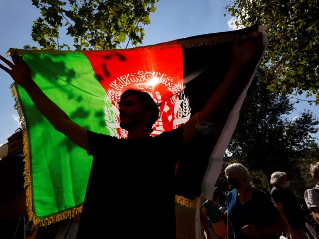 Seorang warga Afghanistan mengibarkan bendera negaranya di kota Paris, Prancis. (REUTERS/Eric Gaillard)