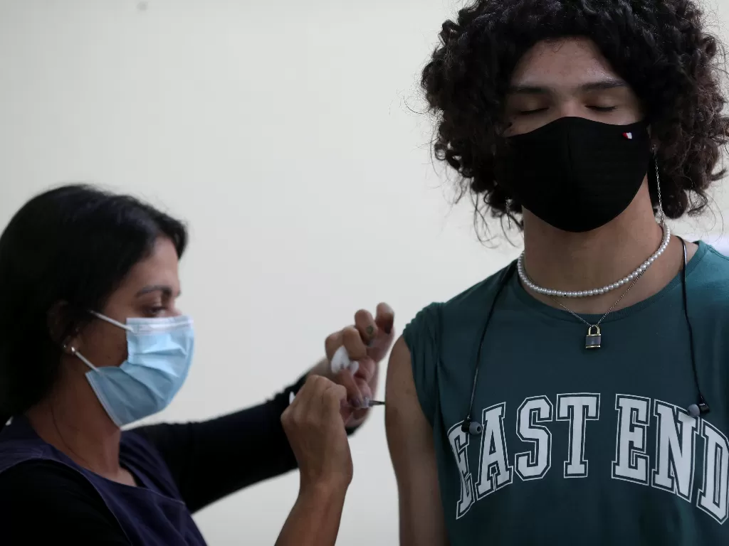 Petugas menyuntikan vaksin Covid-19 buatan Pfizer ke seorang pemuda di Rio de Janeiro, Brasil, Jumat (17/9/2021) (REUTERS/Ricardo Moraes)