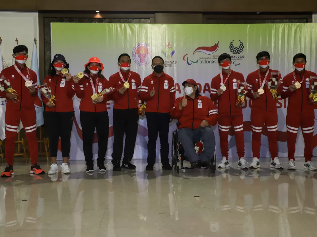  Menpora Zainudin Amali (tengah) bersama Ketua National Paralympic Committee (NPC) Indonesia Senny Marbun (keempat kanan) berfoto bersama para peraih medali, Selasa (7/9). (photo/ANTARA FOTO/Fauzan/ilustrasi).