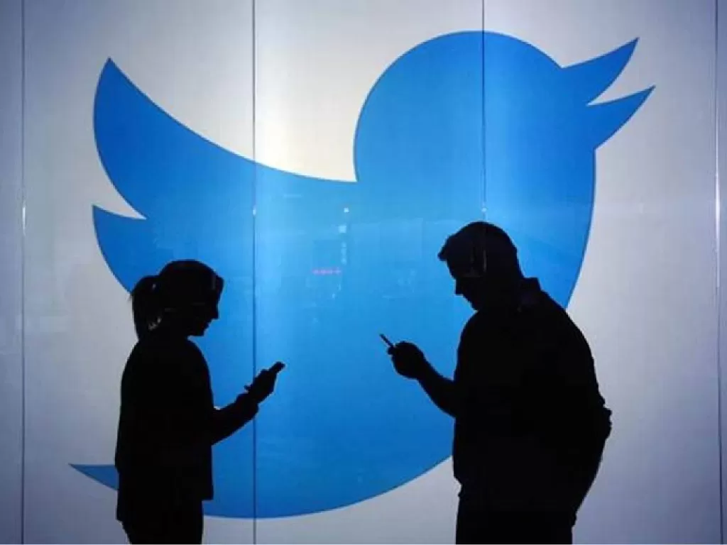 Dua orang sedang menggunakan ponsel di depan logo Twitter (photo/REUTERS)