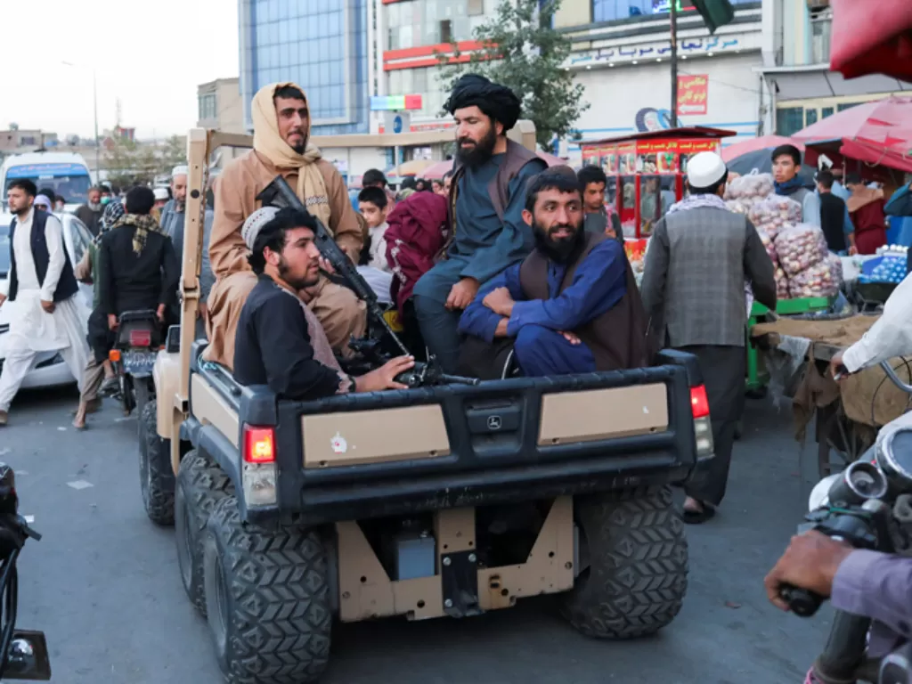 Tentara Taliban sedang duduk di belakang sebuah mobil truk melintasi jalan di Kabul, Afghanistan. (REUTERS/West Asia News Agency)