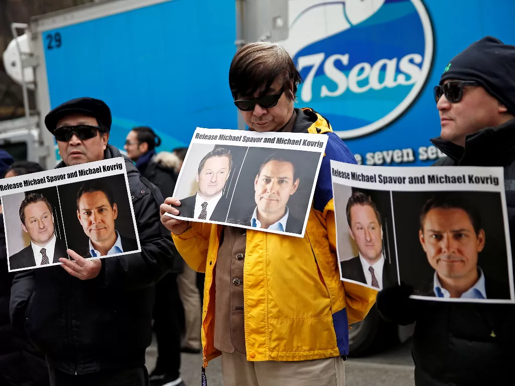 Orang-orang memegang foto Michael Spavor dan Michael Kovrig. (REUTERS/ Lindsey Wasson)