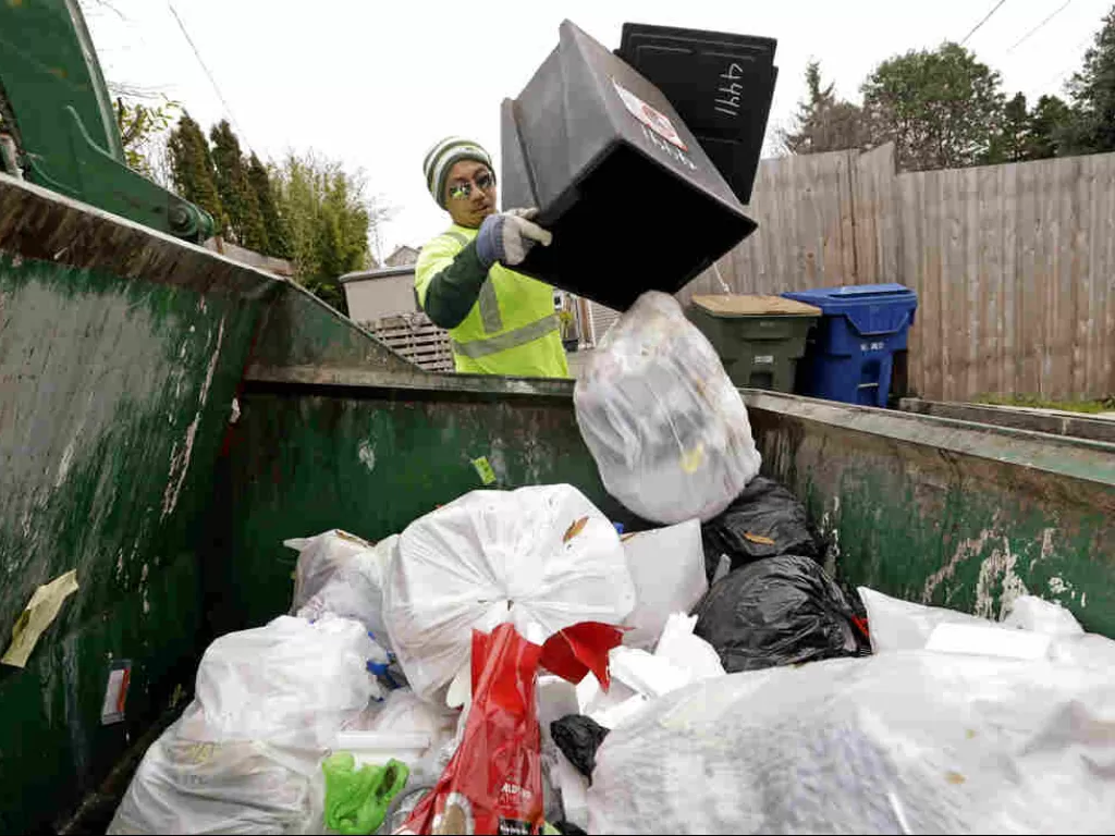 Ilustrasi petugas sampah memindahkan sampah sisa makanan ke dalam bak penampungan sampah. (NPR)