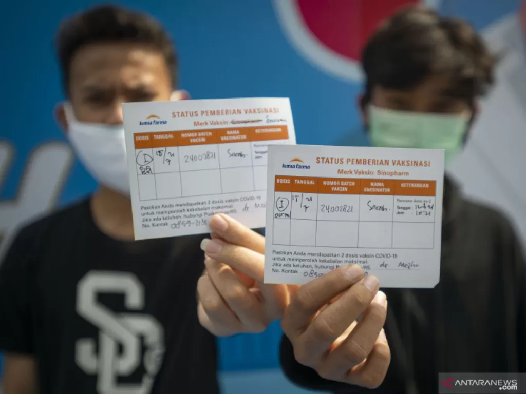 Dua remaja menunjukkan kartu bukti vaksinasi COVID-19 dosis pertama di Jakarta, Kamis (15/7/2021). (ANTARA FOTO/Aditya Pradana Putra)