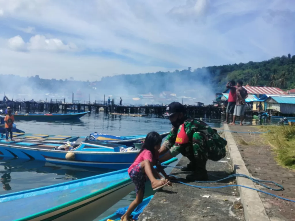 Anggota Koramil 01-1801 di Manokwari membantu memindahkan anak-anak dan perempuan korban kebakaran dari atas kapal motor mesin ke tempat pengungsian sementara, Kamis (30/9/2021) (Antara)