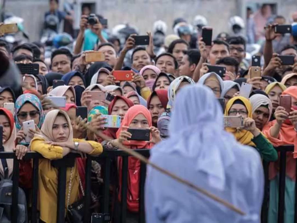 Puluhan warga manyaksikan seorang terpidana pelanggar hukum Syariat Islam menjalani hukuman cambuk di Banda Aceh. (Foto/AP)