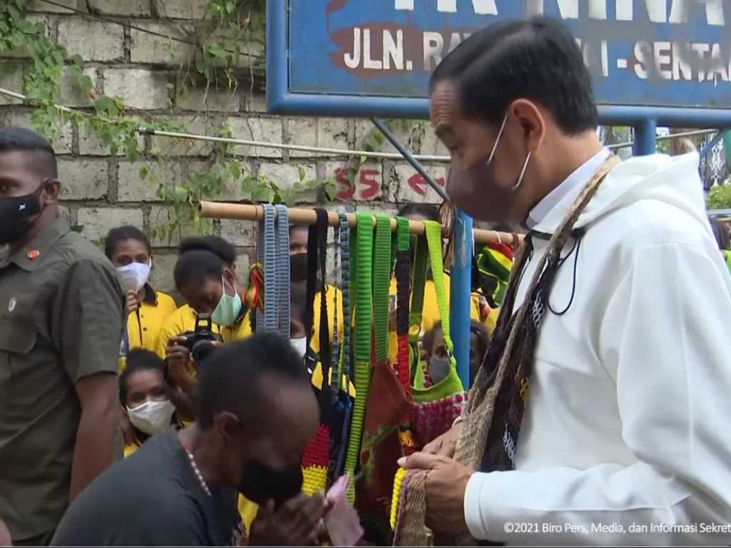 Presiden Jokowi saat membeli noken kerajinan tas asli Papua. (Youtube/Sekretariat Presiden)