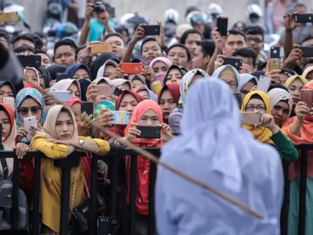 Warga merekam wanita yang dihukum cambuk akibat zina di halaman Masjid Jamik Lueng Bata, Banda Aceh, Aceh, Jumat (20/4). (AP Photo/Heri Juanda)