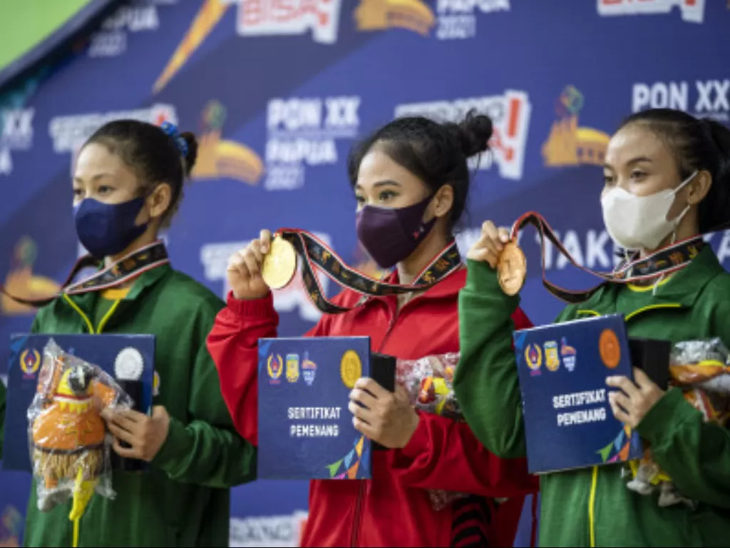 Pesenam artistik putri DKI Jakarta Rifda Irfanaluthfi (tengah) menunjukkan medali emas dari cabang olahraga senam artistik perorangan putri PON Papua,  Minggu (3/10/2021). (ANTARA FOTO/M Risyal Hidayat)