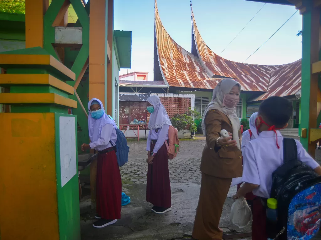  Ilustrasi. Guru memeriksa suhu tubuh siswa sebelum masuk ke sekolah, di SDN Percobaan Padang, Sumatera Barat, Senin (4/10/2021). (photo/ANTARA FOTO/Iggoy el Fitra/ ilustrasi)