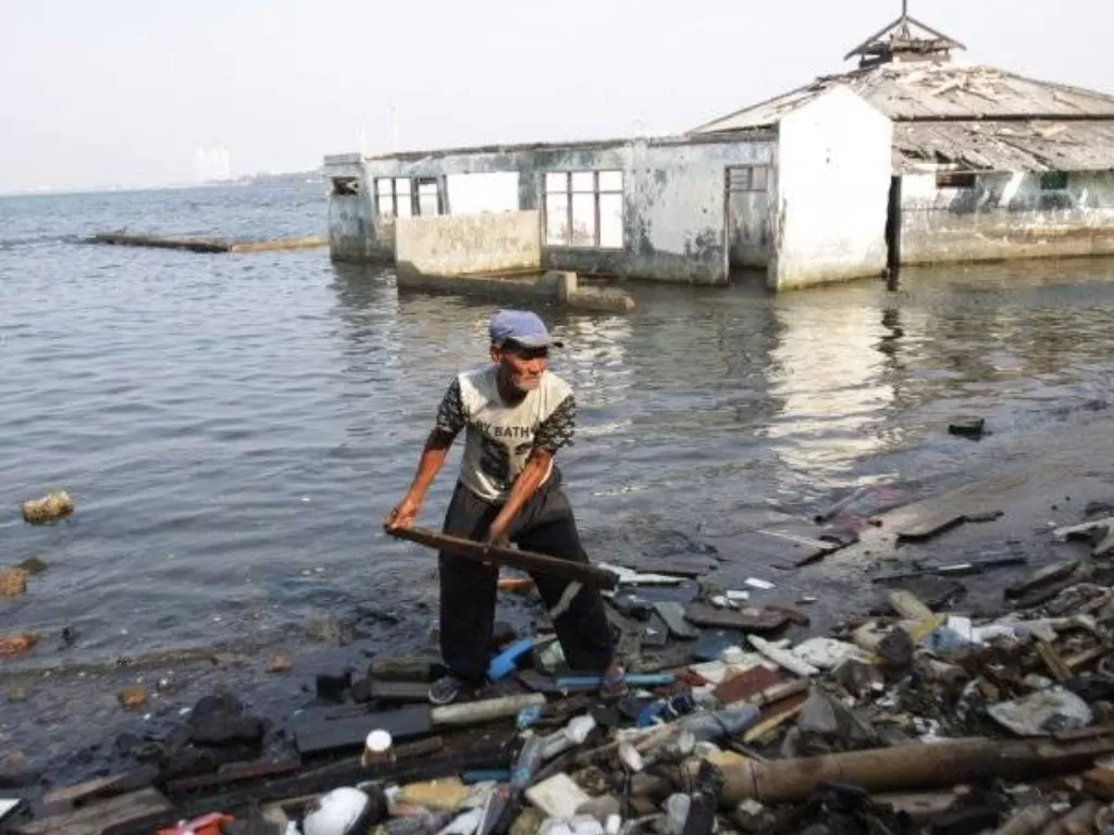 Warga memilah sampah dengan latar bangunan yang tergenang rob (air pasang laut) di Muara Baru, Jakarta Utara. (ANTARA FOTO/Reno Esnir)