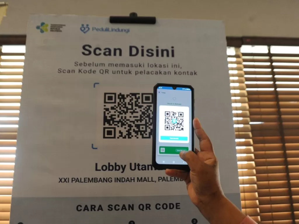 Pengunjung memindai kode batang (QR Code) melalui aplikasi PeduliLindungi sebelum memasuki bioskop di salah Satu Mall Kota Palembang. (ANTARA FOTO/Feny Selly)