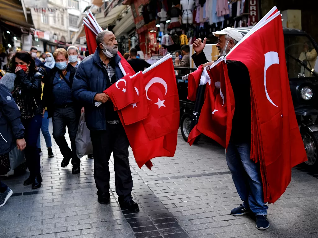 Dua pria lanjut usia berjualan bendera Turki di jalanan ibu kota Istanbul, Selasa (5/10/2021) (REUTERS/Murad Sezer)