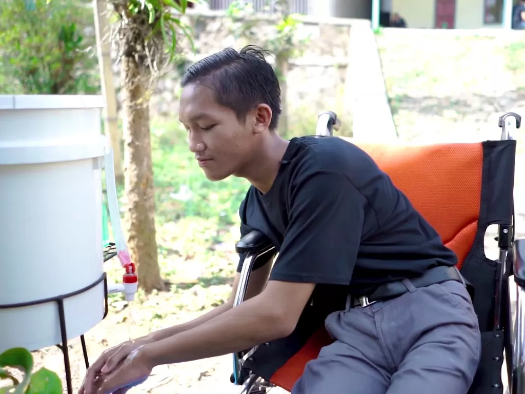 Penyandang disabilitas di Kab. Bandung, Faisal mempraktikkan cuci tangan menggunakan kursi roda. (Save the Children)