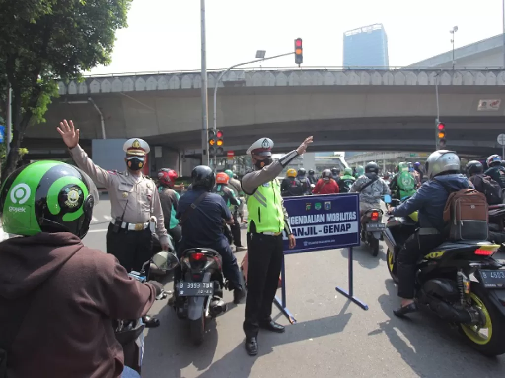 Polisi berjaga untuk mengarahkan kendaraan saat penerapan sistem ganjil genap di Jalan Gatot Subroto, Jakarta. (ANTARA FOTO/Reno Esnir)