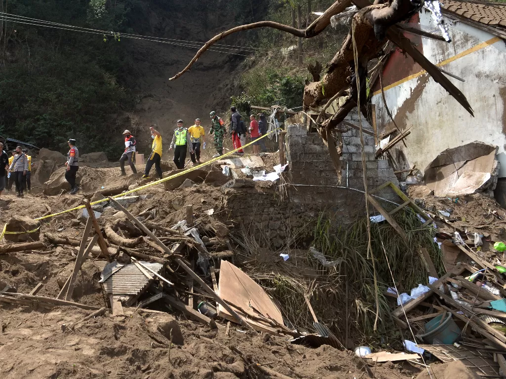Petugas dan warga berjalan di dekat rumah yang rusak tertimbun longsoran bukit akibat gempa di kawasan Trunyan, Kintamani, Bangli, Bali, Sabtu (16/10/2021). (ANTARA/Fikri Yusuf)