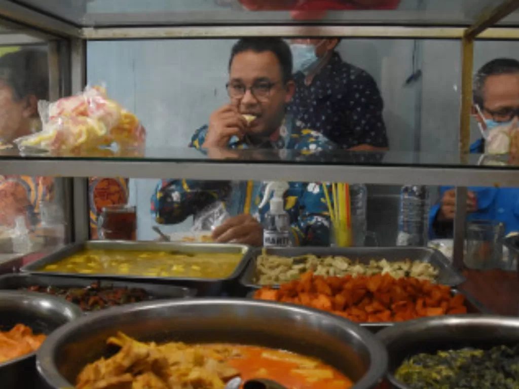Gubernur DKI Jakarta Anies Baswedan (tengah) menikmati makan siang di salah satu warteg. (ANTARA FOTO/Indrianto Eko Suwarso)
