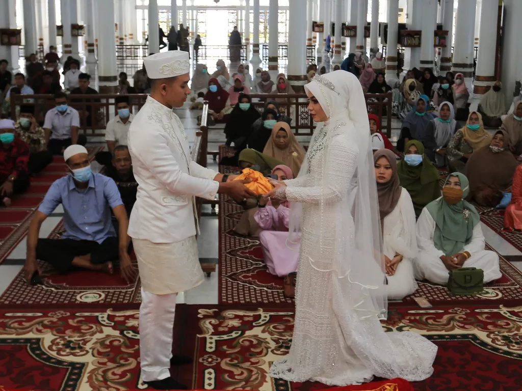  Pasangan pengantin menyerahkan mahar seusai melaksanakan prosesi ijab kabul di Masjid Raya Baiturrahman, Banda Aceh, Aceh, Kamis (23/9/2021). (photo/ANTARA FOTO/Syifa Yulinnas/ilustrasi)