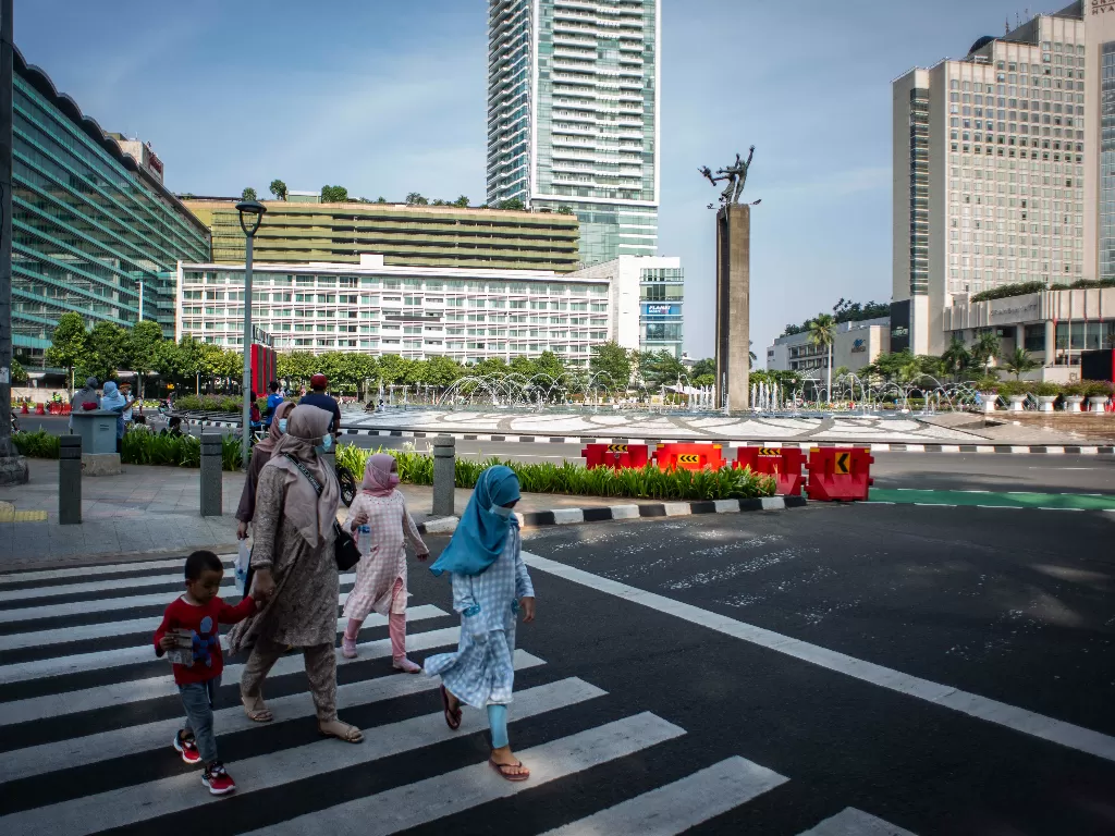 Sejumlah warga berjalan di kawasan Bundaran HI, Jakarta, Minggu (10/10/2021). Aktivitas warga di kawasan tersebut relatif ramai saat penerapan Pemberlakuan Pembatasan Kegiatan Masyarakat (PPKM) di ibu kota. (ANTARA FOTO/Aprillio Akbar)