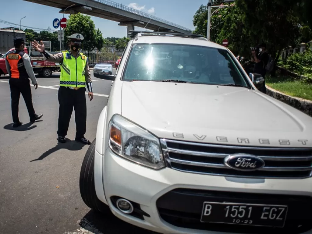 Petugas Satlantas Polres Metro Jakarta Timur mempersilahkan kendaraan berplat nomor ganjil untuk berputar arah. (ANTARA FOTO/Aprillio Akbar)