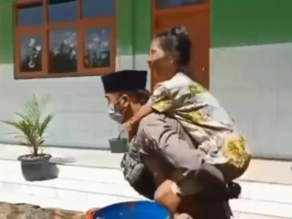 Bripka Hamsun Bisri gendong warga disabilitas ke lokasi vaksin di Sumenep (Instagram/andreli48) 