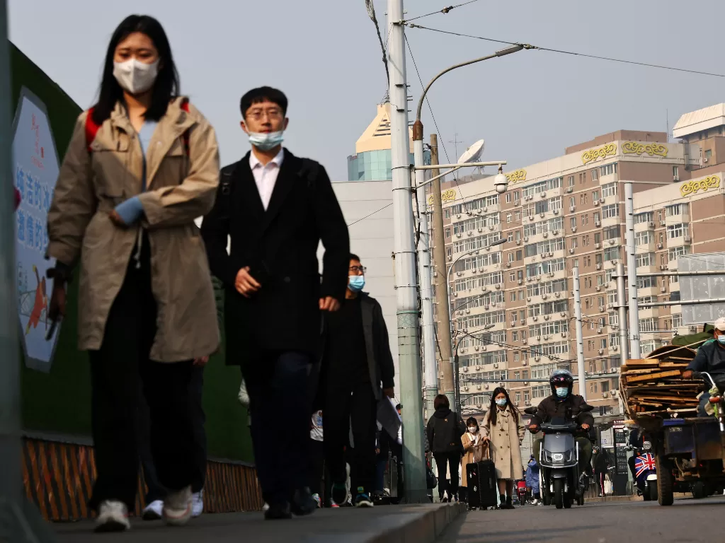 Orang-orang berjalan menggunakan masker di jalan Beijing. (REUTERS/Thomas Peter)