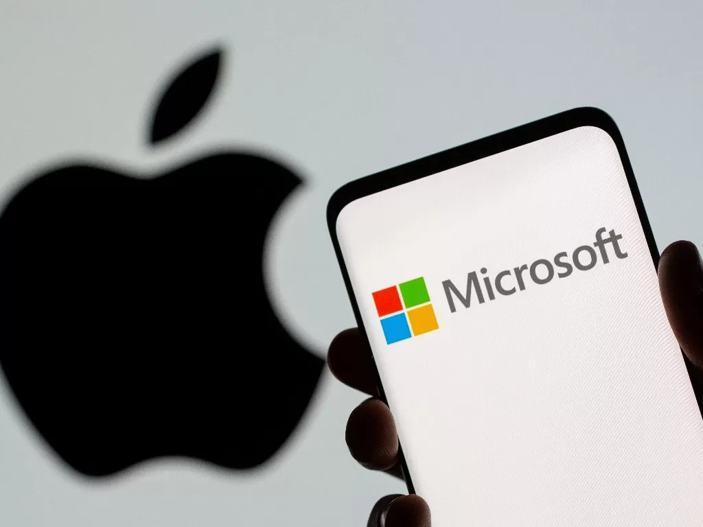 Logo Microsoft terlihat pada smartphone di depan logo Apple yang ditampilkan dalam ilustrasi yang diambil, 26 Juli 2021.  (photo/REUTERS/Dado Ruvic/ilustrasi)