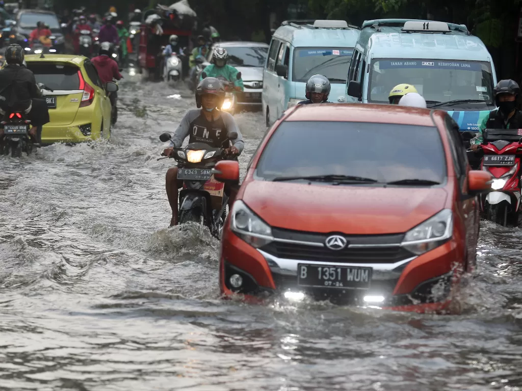 Pengendara menerobos banjir di Jalan Raya Banjir yang menggenangi jalan setinggi lutut orang dewasa itu disebabkan karena drainase buruk saat terjadi hujan deras. (Foto: ANTARA/Muhammad Iqbal)