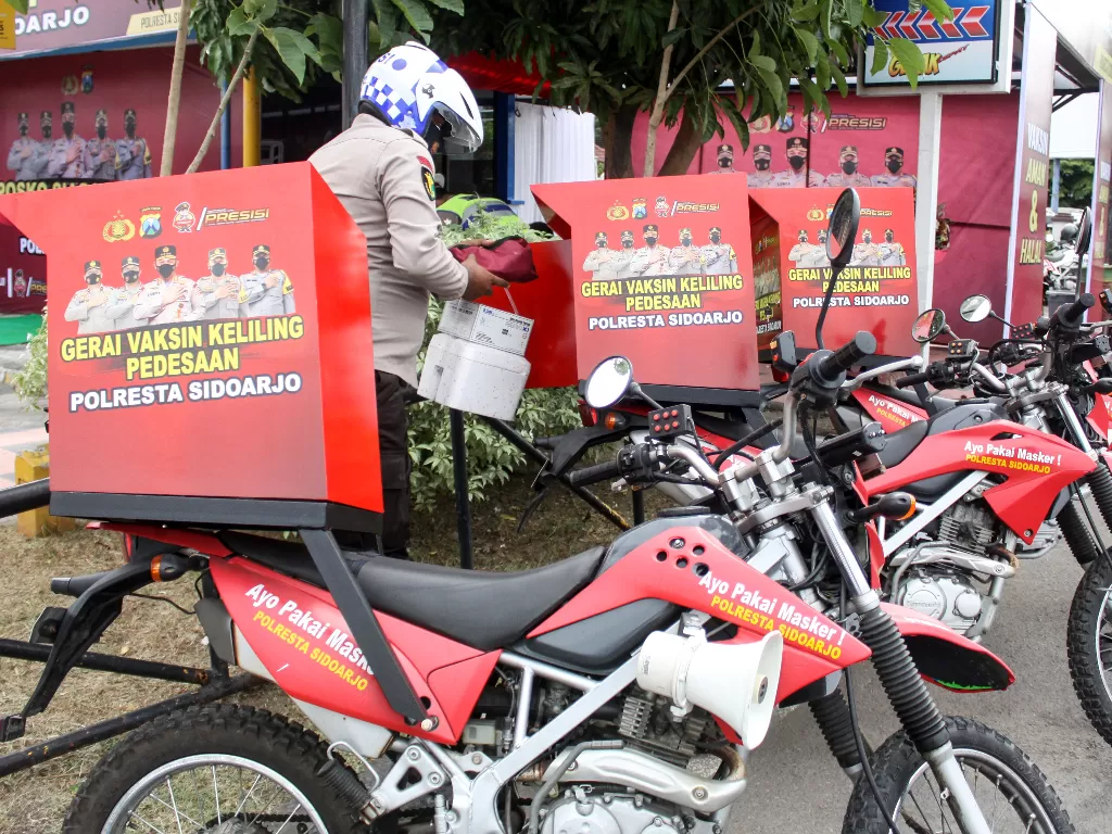 Petugas menyiapkan peralatan vaksinasi di motor roda dua keliling di Posko Siaga Vaksin 24 Jam, kawasan Pos Polisi Bundaran Taman Pinang Indah, Sidoarjo, Jawa Timur. (ANTARA FOTO/Umarul Faruq).