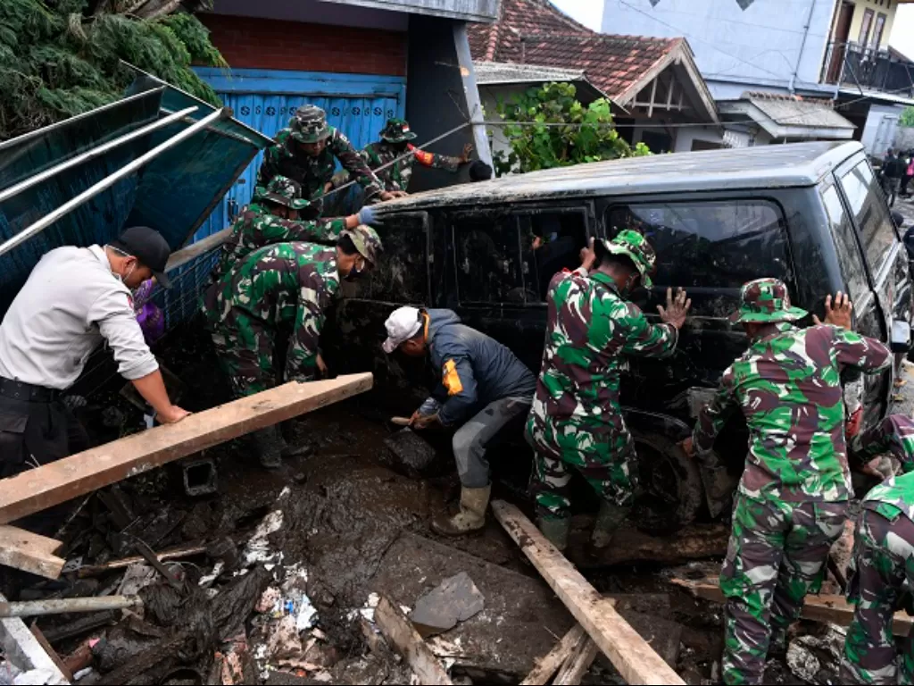Anggota Polisi dan TNI berusaha mengamankan sebuah mobil yang terperosok akibat banjir bandang di Bulukerto, Kota Batu. (ANTARA FOTO/Zabur Karuru)