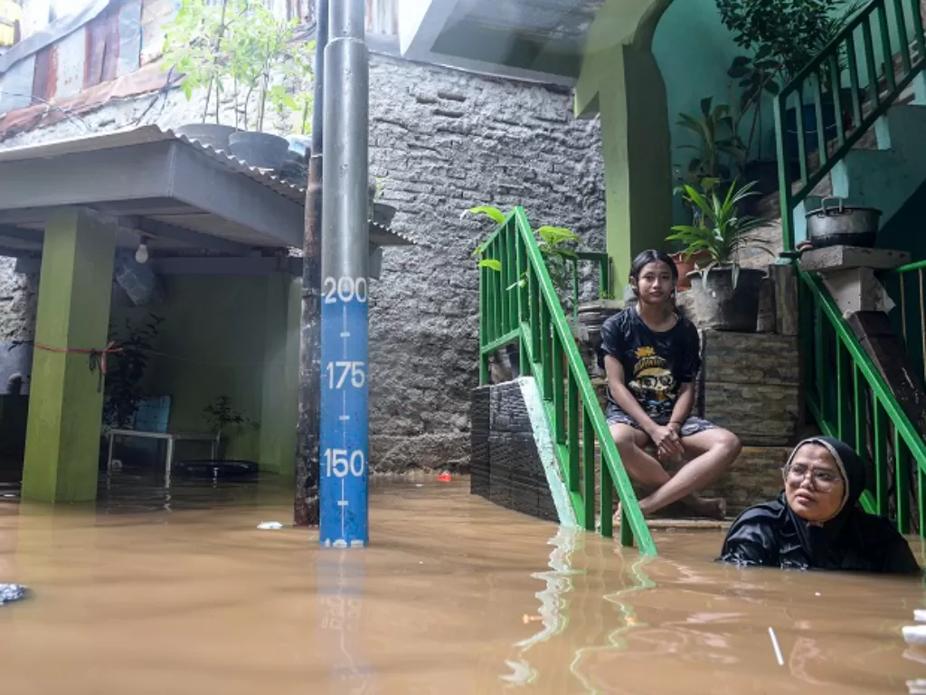 Dua orang warga berada di anak tangga ketika banjir merendam di kawasan Kebon Pala, Kampung Melayu, Jakarta Timur. (ANTARA FOTO/M Risyal Hidayat)