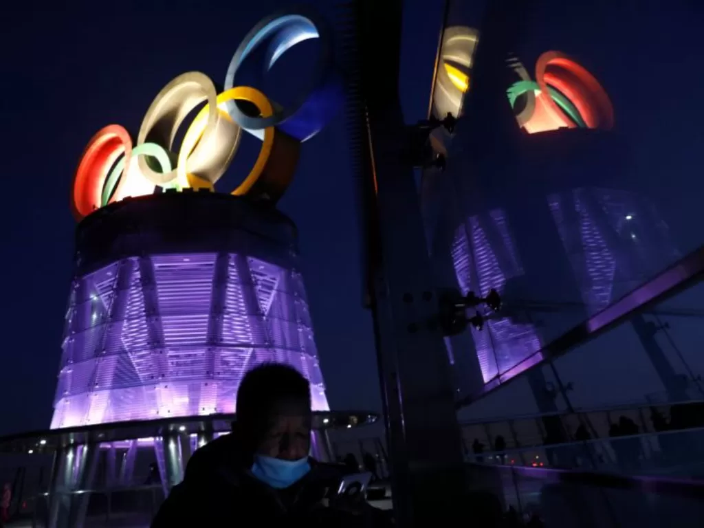 Seorang pria menggunakan masker mengikuti aturan pandemi COVID-19 terlihat di dekat logo cincin Olimpiade di Olympic Tower, setahun jelang pembukaan Olimpiade Musim Dingin 2022 di Beijing, China, pada 4 Februari 2021. (ANTARA/REUTERS/Tingshu Wang)