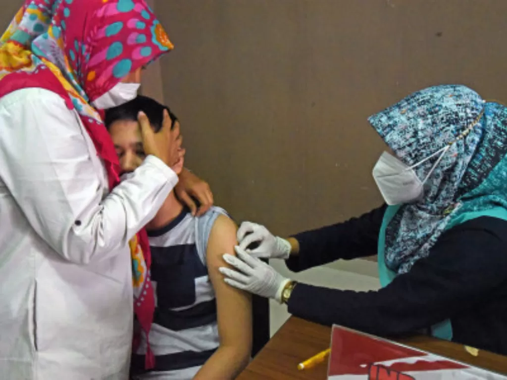 Relawan yang tergabung dalam Gerakan Indonesia Pasti Bisa (GIPB) menenangkan warga yang disuntik vaksin COVID-19 saat vaksinasi keliling di Gedung Training Center UPI di Serang, Banten, Sabtu (13/11/2021). (ANTARA FOTO/Asep Fathulrahman)