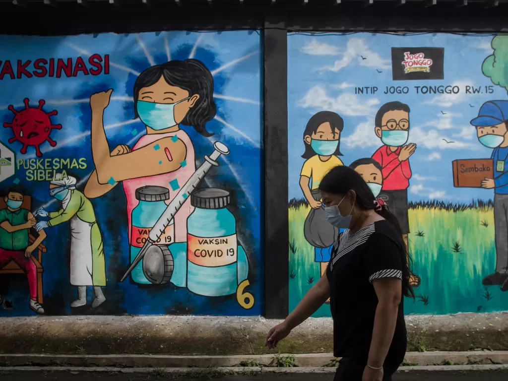 Warga berjalan di depan mural bertema penanganan COVID-19 di Mojosongo, Solo, Jawa Tengah (ANTARA FOTO/Mohammad Ayudha/aww.)