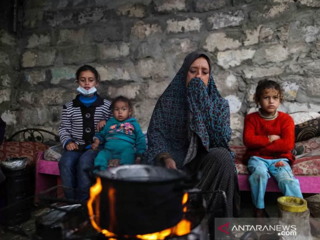 Warga Palestina menghangatkan diri di sekitar api tungku di area permukiman kumuh sebuah kamp pengungsi saat cuaca badai di Kota Khan Younis, Jalur Gaza selatan, Kamis (26/11/2020). (ANTARA FOTO/Xinhua/Yasser Qudih)