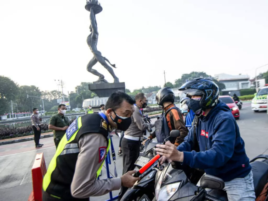Anggota Polisi mengacungkan jempol pada pengendara mobil yang menunjukkan surat undangan vaksin Covid-19 di Gelora Bung Karno. (ANTARA FOTO/M Risyal Hidayat)
