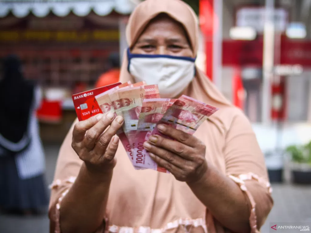 Warga menunjukkan uang bantuan sosial tunai atau BST usai mengambil di ATM Bank DKI (ANTARA FOTO/Rivan Awal Lingga/foc.)