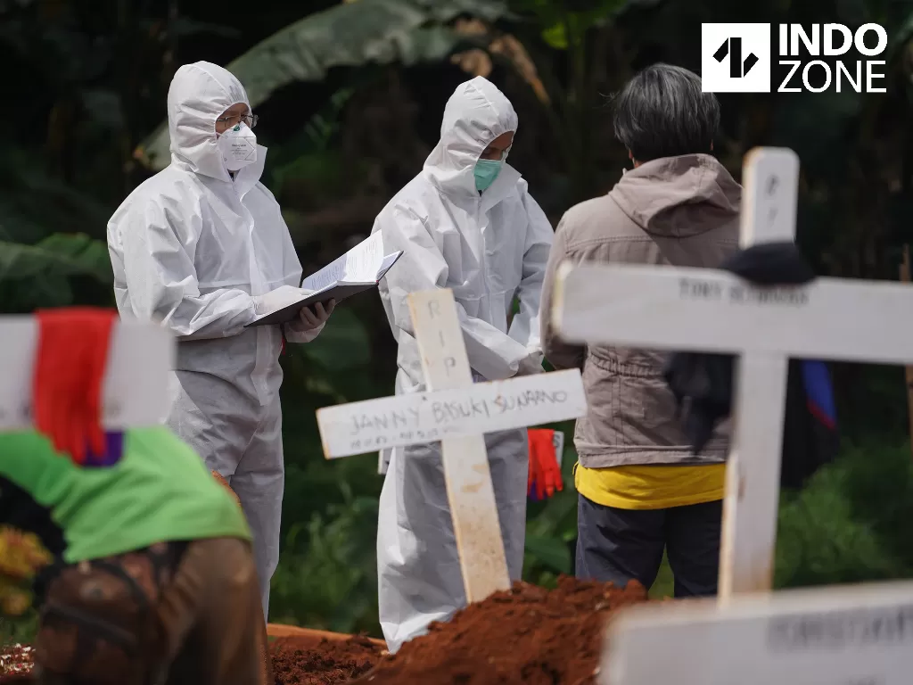 Petugas pemakaman membawa peti jenazah pasien Covid-19 di TPU Pondok Ranggon, Jakarta. (INDOZONE).