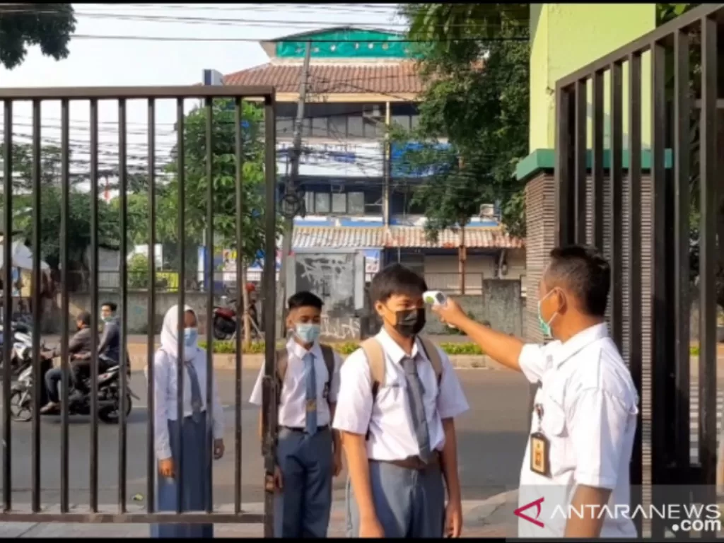 Seorang petugas mengecek suhu badan siswa pada hari pertama pembelajaran tatap muka (PTM) terbatas di SMK Negeri 32 Jakarta, Tebet Dalam, Jakarta Selatan, Senin (30/8/2021). (ANTARA/Sihol Hasugian)