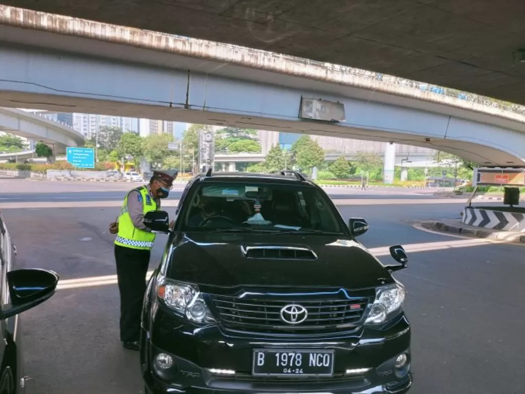 Polisi menilang pengendara yang melanggar ketentuan Ganjil Genap di Jalan Raya Tomang, Jakarta Barat, Jumat (29/1/2021).(ANTARA/Walda)