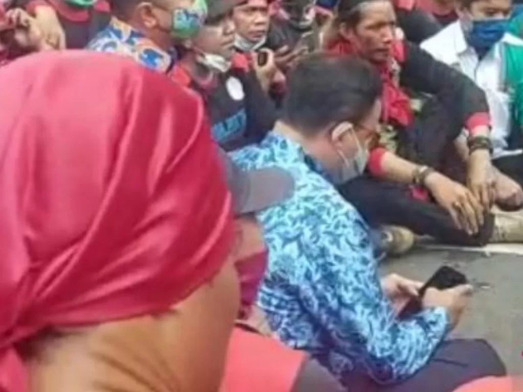 Gubernur DKI Jakarta Anies Baswedan duduk di aspal di Jalan Merdeka Selatan saat menemui massa buruh yang beraksi menolak UMP, Senin (29/11/2021). (Foto: Antara/Mentari Dwi Gayati)
