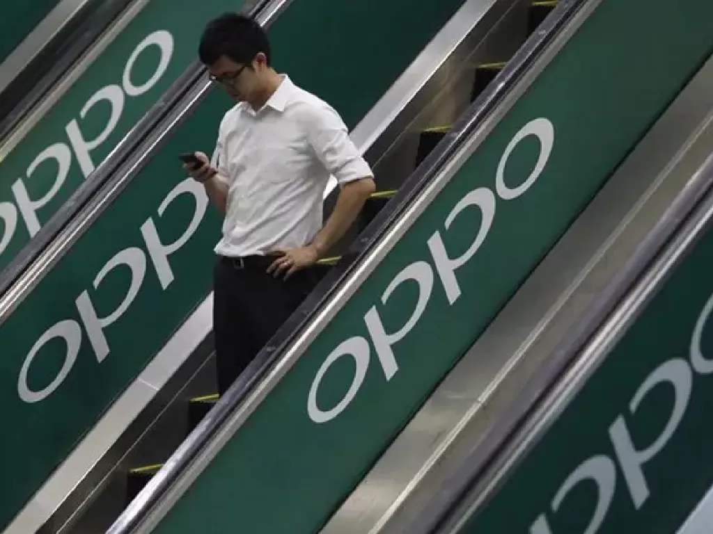 Tampilan seseorang yang sedang menaiki eskalator dengan logo Oppo (photo/REUTERS/Edgar Su)