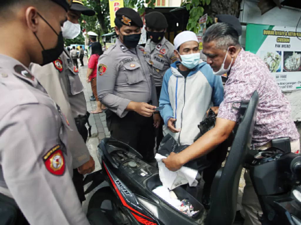 Polisi memeriksa barang bawaan pengendara motor saat dilakukan penyekatan pergerakan massa di Kreo, Tangerang, Banten, untuk mengantisipasi pergerakan massa mengikuti Reuni 212 di Jakarta. (ANTARA FOTO/Muhammad Iqbal/hp)