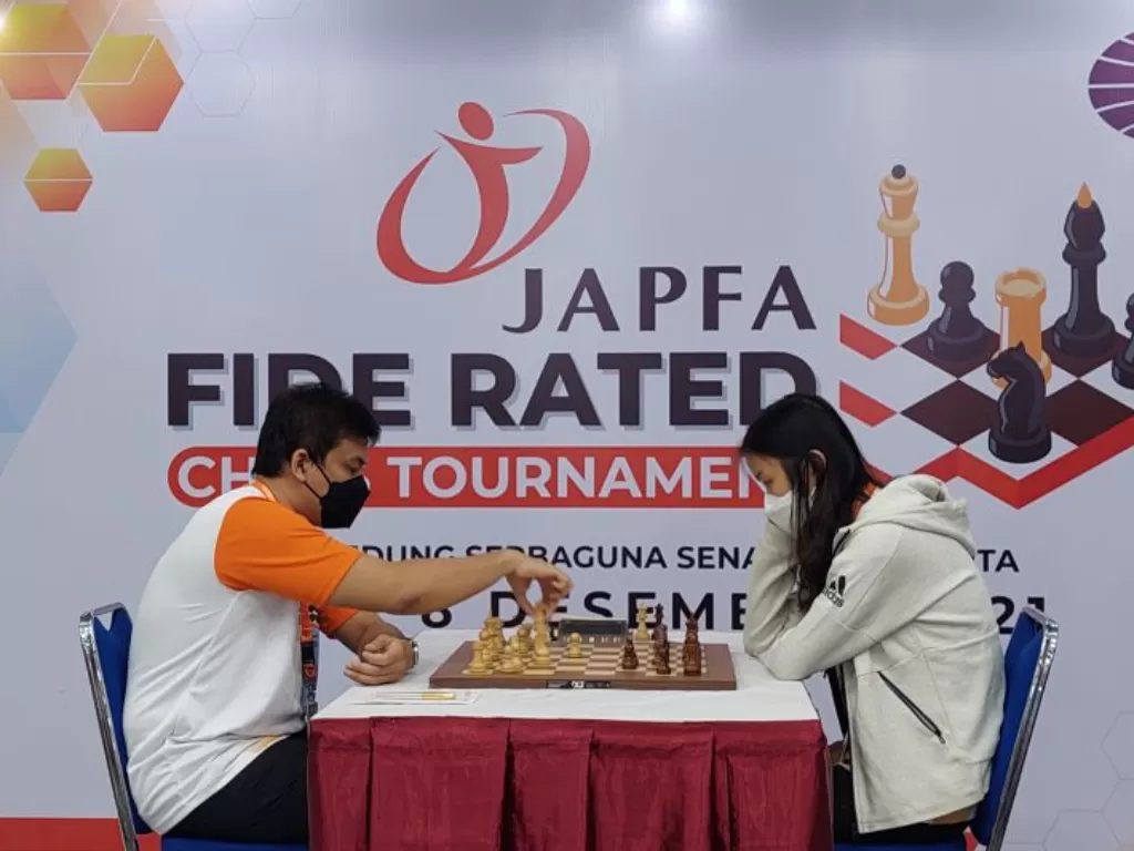 GM Susanto Megaranto (kiri) saat berhadapan dengan WFM Elisabeth Christine pada babak pertama JAPFA FIDE RATED Chess Tournament 2021 di Gedung Serbaguna Senayan, Jakarta, Sabtu (4/12/2021) (ANTARA/Muhammad Ramdan)