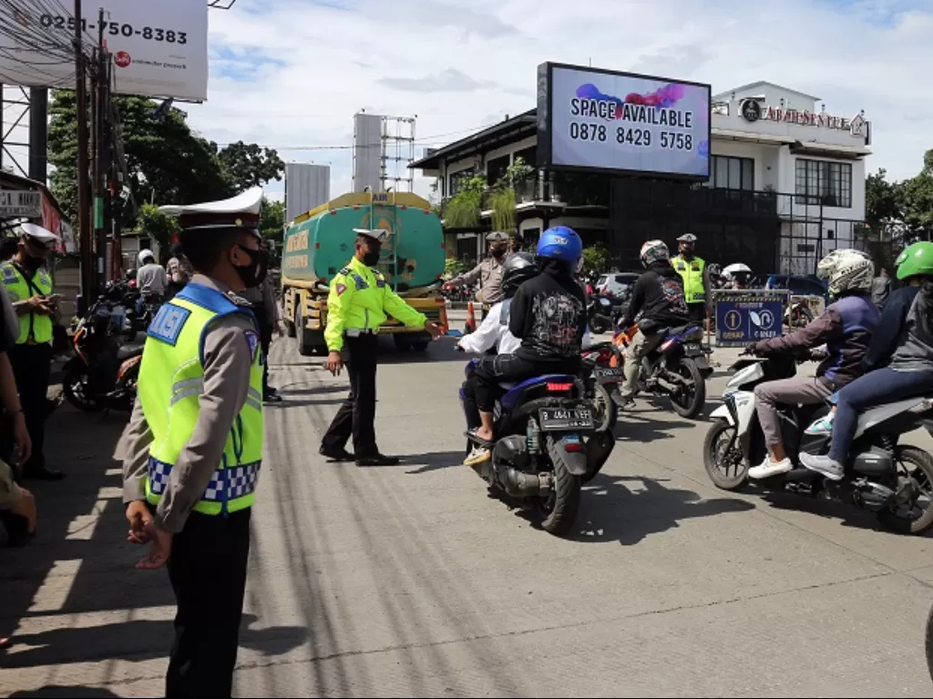 Polisi menghentikan pengendara sepeda motor dengan plat nomor ganjil saat penerapan sistem ganjil genap, (ANTARA FOTO/Yulius Satria Wijaya)